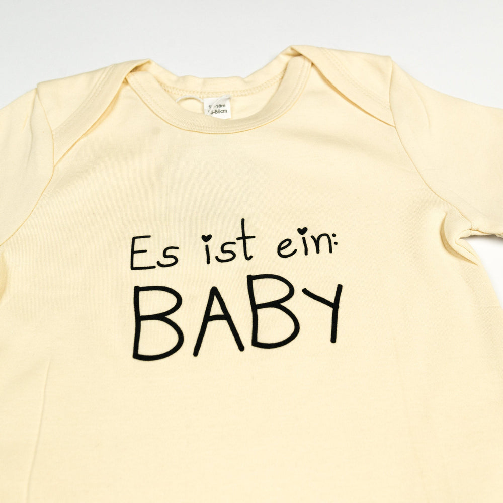 
                  
                    Baby Body aus Bio Baumwolle mit - Es ist ein Baby - Druck aus flauschigem Flock, unisex babykleidung, Strampler baby Geschenk Geburt, Natur
                  
                